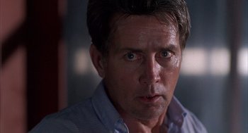Movie still from “The Believers” (1987), directed by John Schlesinger – A man's face in a blue shirt; Close Up shot, Over the shoulder angle