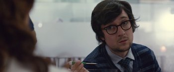 Movie still from “The Belko Experiment” (2016), directed by Greg McLean – A man with glasses holding a pencil and looking at the camera; Close Up shot, Over the shoulder angle