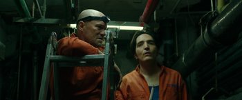 Movie still from “The Belko Experiment” (2016), directed by Greg McLean – A man and a woman wearing orange work clothes; Medium shot, Low angle