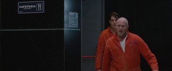 Movie still from “The Belko Experiment” (2016), directed by Greg McLean – Two men in red shirts are walking in a building; Medium shot, Over the shoulder angle