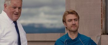 Movie still from “The Belko Experiment” (2016), directed by Greg McLean – A person wearing headphones near a building; Close Up shot, Low angle