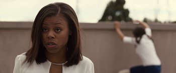 Movie still from “The Belko Experiment” (2016), directed by Greg McLean – A young woman is standing in front of a wall; Close Up shot, Over the shoulder angle