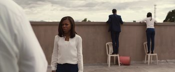 Movie still from “The Belko Experiment” (2016), directed by Greg McLean – A woman standing next to a man on a balcony; Medium shot, Low angle