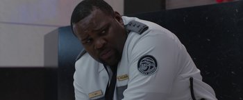 Movie still from “The Belko Experiment” (2016), directed by Greg McLean – A man in a white uniform sitting in a chair; Close Up shot, Over the shoulder angle