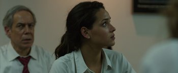 Movie still from “The Belko Experiment” (2016), directed by Greg McLean – A young woman with long dark brown hair wearing a white dress shirt; Close Up shot, Over the shoulder angle