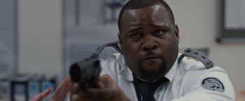 Movie still from “The Belko Experiment” (2016), directed by Greg McLean – A man in a white shirt holding a gun; Close Up shot, Low angle