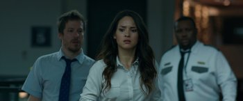 Movie still from “The Belko Experiment” (2016), directed by Greg McLean – A woman in a white shirt is walking with two other men; Close Up shot, Over the shoulder angle