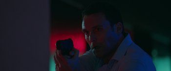 Movie still from “The Belko Experiment” (2016), directed by Greg McLean – A man is holding a gun in a dark room; Close Up shot, Low angle