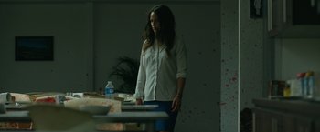 Movie still from “The Belko Experiment” (2016), directed by Greg McLean – A woman standing in front of a table with food on it; Medium shot, Low angle