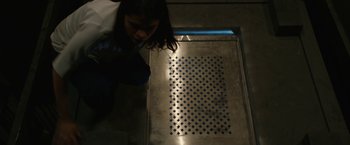 Movie still from “The Belko Experiment” (2016), directed by Greg McLean – A woman standing in front of a metal floor; Wide shot, Overhead angle