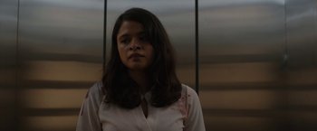 Movie still from “The Belko Experiment” (2016), directed by Greg McLean – A woman with long dark hair wearing a white shirt; Close Up shot, Low angle