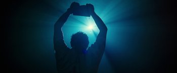 Movie still from “The Belko Experiment” (2016), directed by Greg McLean – A person holding a cell phone up in the air; Medium shot, Low angle