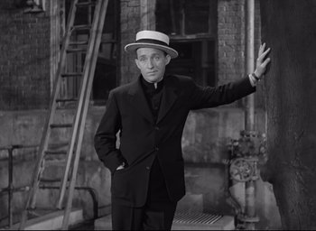 Movie still from “The Bells of St. Mary's” (1945), directed by Leo McCarey – A man in a suit and hat standing in front of a building; Medium shot, Low angle