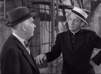 Movie still from “The Bells of St. Mary's” (1945), directed by Leo McCarey – A man in a suit and a man in a hat shake hands; Medium shot, Over the shoulder angle