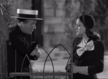 Movie still from “The Bells of St. Mary's” (1945), directed by Leo McCarey – A man and a woman talking to each other in front of an iron fence; Medium shot, High angle