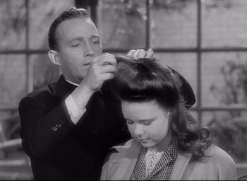 Movie still from “The Bells of St. Mary's” (1945), directed by Leo McCarey – An old photo of a man and a woman getting their hair done; Close Up shot, High angle