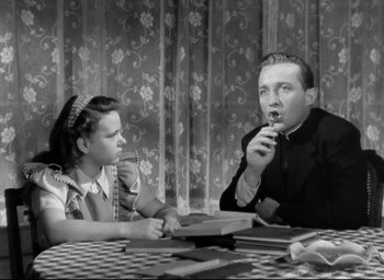 Movie still from “The Bells of St. Mary's” (1945), directed by Leo McCarey – A man and a girl sitting at a dining table; Medium shot, Low angle
