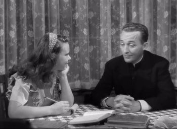 Movie still from “The Bells of St. Mary's” (1945), directed by Leo McCarey – An old photo of a man and a woman sitting at a table; Medium shot, High angle