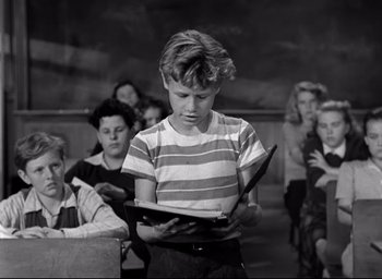 Movie still from “The Bells of St. Mary's” (1945), directed by Leo McCarey – Black and white photograph of a young boy reading a book; Medium shot, Low angle