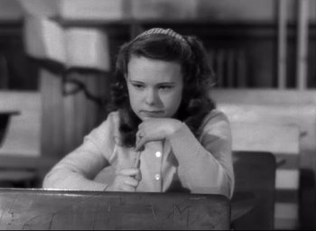 Movie still from “The Bells of St. Mary's” (1945), directed by Leo McCarey – A young girl sitting at a table with her head resting on her hands; Close Up shot, High angle