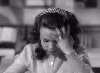 Movie still from “The Bells of St. Mary's” (1945), directed by Leo McCarey – A young woman with a checkered head band is holding her hand to her head; Close Up shot, High angle