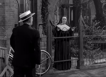 Movie still from “The Bells of St. Mary's” (1945), directed by Leo McCarey – An old photo of a man and a nun in front of a gate; Wide shot, Low angle