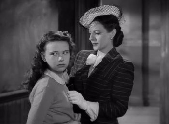 Movie still from “The Bells of St. Mary's” (1945), directed by Leo McCarey – An older woman helping a young girl with a hat; Medium shot, Over the shoulder angle