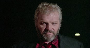 Movie still from “The Belly of an Architect” (1987), directed by Peter Greenaway – A person wearing a suit and tie; Close Up shot, Low angle