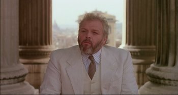 Movie still from “The Belly of an Architect” (1987), directed by Peter Greenaway – An older man wearing a white suit and a brown tie; Medium shot, Low angle