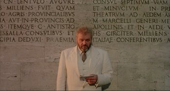 Movie still from “The Belly of an Architect” (1987), directed by Peter Greenaway – A man in a white suit is holding a cell phone; Medium shot, Low angle