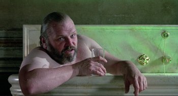 Movie still from “The Belly of an Architect” (1987), directed by Peter Greenaway – A shirtless man holding a glass in a bath tub; Close Up shot, Low angle