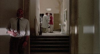 Movie still from “The Belly of an Architect” (1987), directed by Peter Greenaway – Two people standing in a hallway talking to each other; Wide shot, Over the shoulder angle