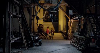 Movie still from “The Belly of an Architect” (1987), directed by Peter Greenaway – Two people are walking down the stairs of a building; Extreme Wide shot, High angle