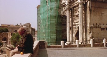 Movie still from “The Belly of an Architect” (1987), directed by Peter Greenaway – A building that has been wrapped in scaffolding for repairs; Wide shot, Low angle