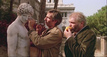 Movie still from “The Belly of an Architect” (1987), directed by Peter Greenaway – A couple of people that are eating some food; Medium shot, Low angle