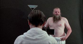 Movie still from “The Belly of an Architect” (1987), directed by Peter Greenaway – A man with a long beard is in front of a mirror; Medium shot, Over the shoulder angle