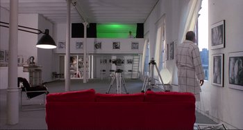 Movie still from “The Belly of an Architect” (1987), directed by Peter Greenaway – A red couch in a room with a green screen in the background; Extreme Wide shot, High angle