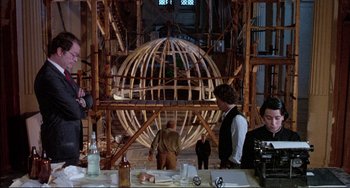 Movie still from “The Belly of an Architect” (1987), directed by Peter Greenaway – A group of people standing in a room with a wooden structure; Wide shot, Low angle
