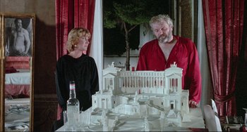 Movie still from “The Belly of an Architect” (1987), directed by Peter Greenaway – A man and a woman standing in front of a model of an ancient city; Medium shot, Low angle