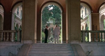 Movie still from “The Belly of an Architect” (1987), directed by Peter Greenaway – Two men are standing in front of an archway; Extreme Wide shot, Low angle