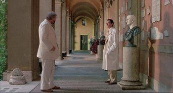 Movie still from “The Belly of an Architect” (1987), directed by Peter Greenaway – Two men are standing in front of a statue; Wide shot, Low angle