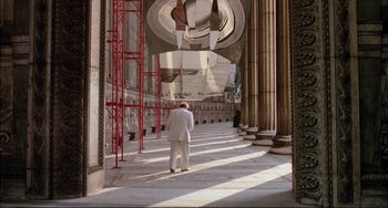 Movie still from “The Belly of an Architect” (1987), directed by Peter Greenaway – A man in a white suit walking down a street; Extreme Wide shot, Low angle