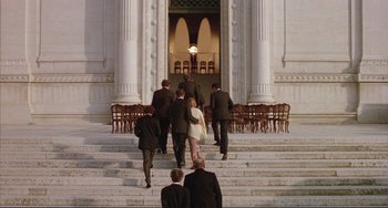 Movie still from “The Belly of an Architect” (1987), directed by Peter Greenaway – A group of people walking down a set of stairs; Extreme Wide shot, High angle