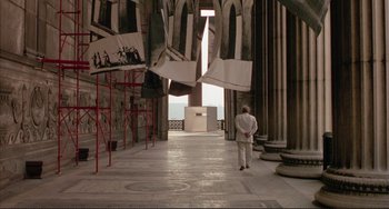 Movie still from “The Belly of an Architect” (1987), directed by Peter Greenaway – A man in a white suit is standing in an old building; Extreme Wide shot, High angle