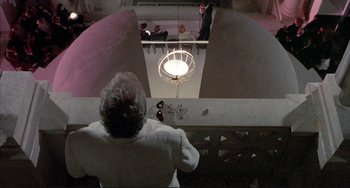 Movie still from “The Belly of an Architect” (1987), directed by Peter Greenaway – A man standing on top of a flight of stairs; Wide shot, Overhead angle