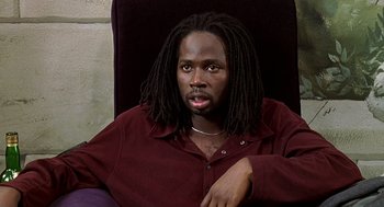 Movie still from “The Best Man” (1999), directed by Malcolm D. Lee – A man sitting in a chair wearing a maroon shirt; Close Up shot, High angle