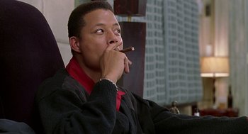Movie still from “The Best Man” (1999), directed by Malcolm D. Lee – A man sitting in a chair with a cigar in his mouth; Close Up shot, Low angle