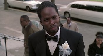 Movie still from “The Best Man” (1999), directed by Malcolm D. Lee – A man in a suit and a bow tie standing in front of other men; Close Up shot, Low angle