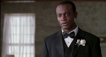 Movie still from “The Best Man” (1999), directed by Malcolm D. Lee – A man in a black suit and a black bow tie; Close Up shot, Over the shoulder angle