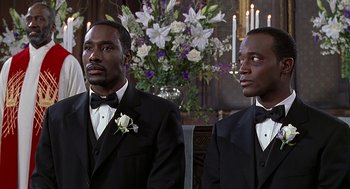 Movie still from “The Best Man” (1999), directed by Malcolm D. Lee – A couple of men in tuxedos standing next to each other; Medium shot, Low angle